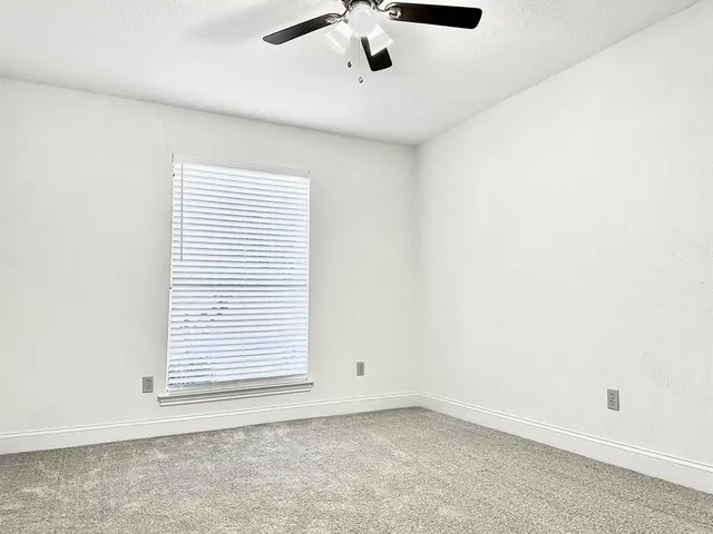 an empty room with a window and a ceiling fan