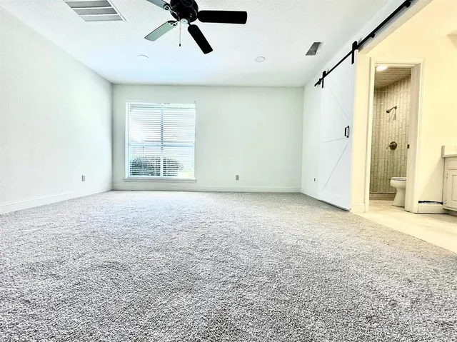 an empty room with a ceiling fan and windows