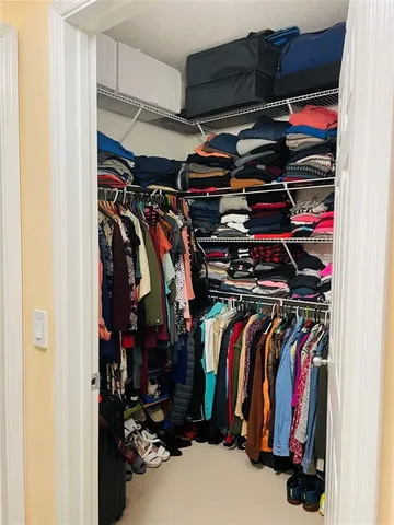 a view of walk in closet with clothes and shoes