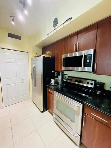 a kitchen with stainless steel appliances granite countertop a refrigerator and a stove top oven