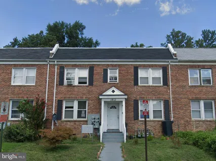 a view of a brick house with a yard plants and a large tree