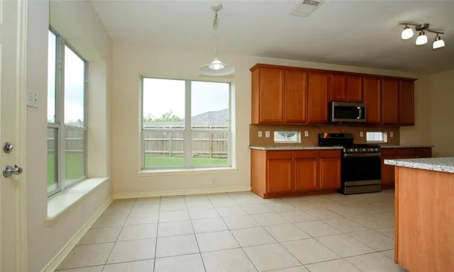 a kitchen with stainless steel appliances granite countertop a stove a sink dishwasher and a refrigerator with wooden cabinets