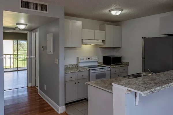 a kitchen with granite countertop a sink stove and refrigerator