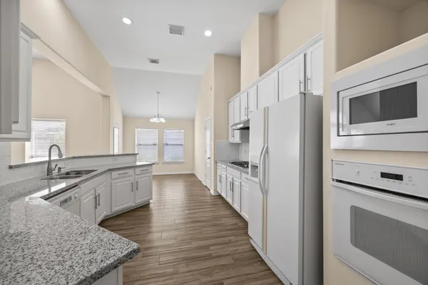 a kitchen with stainless steel appliances granite countertop a refrigerator a stove and a sink