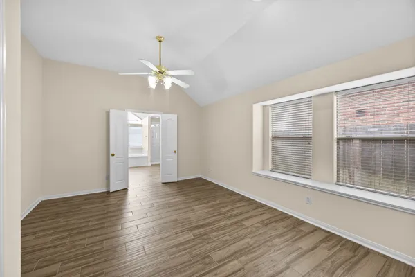 a view of an empty room with a window and wooden floor