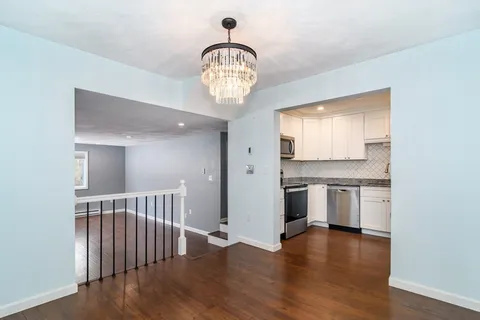 a view of a kitchen with a sink and dishwasher a stove top oven with wooden floor