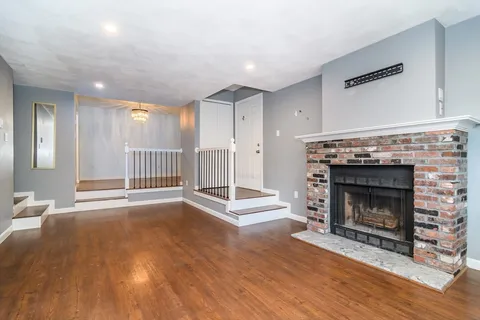 a living room with wooden floor and a fireplace
