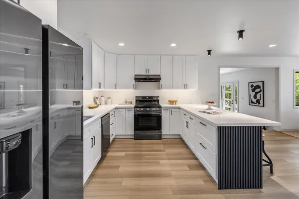 a kitchen with granite countertop white cabinets and white stainless steel appliances