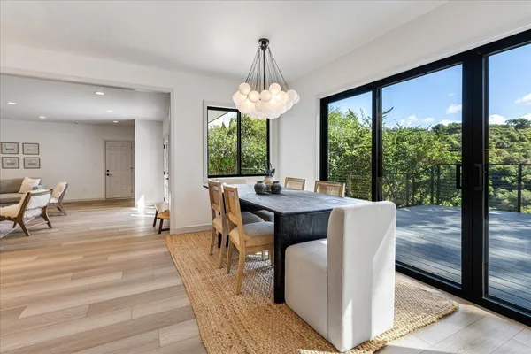 a dining room with wooden floor a chandelier a glass table and chairs