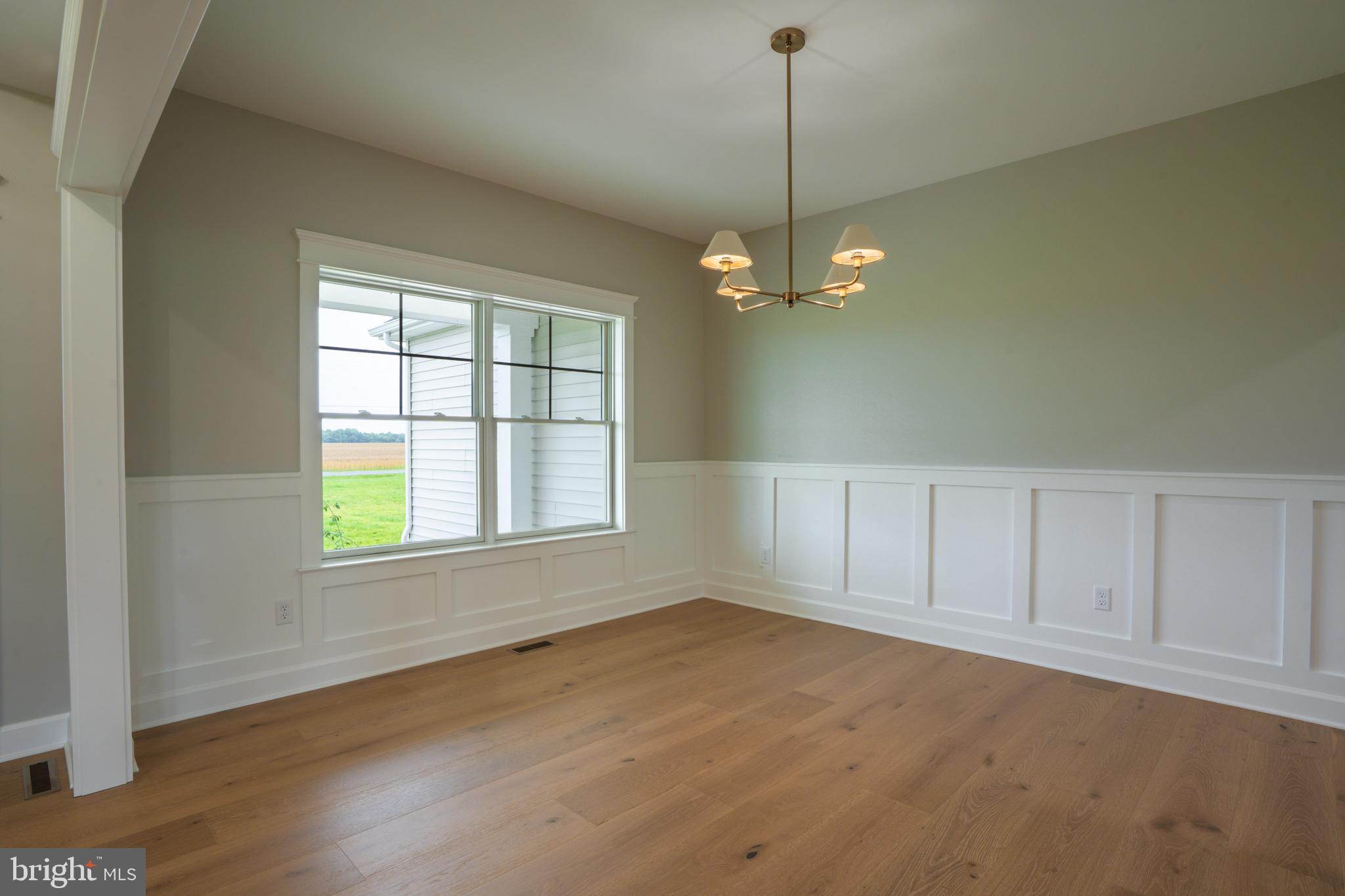 22430 Hummingbird Road Ellendale, DE 19941 - Photo 21 of 39 an empty room with wooden floor exposed radiator and windows