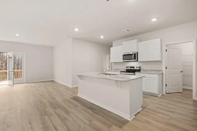 a kitchen with kitchen island granite countertop a sink cabinets and wooden floor