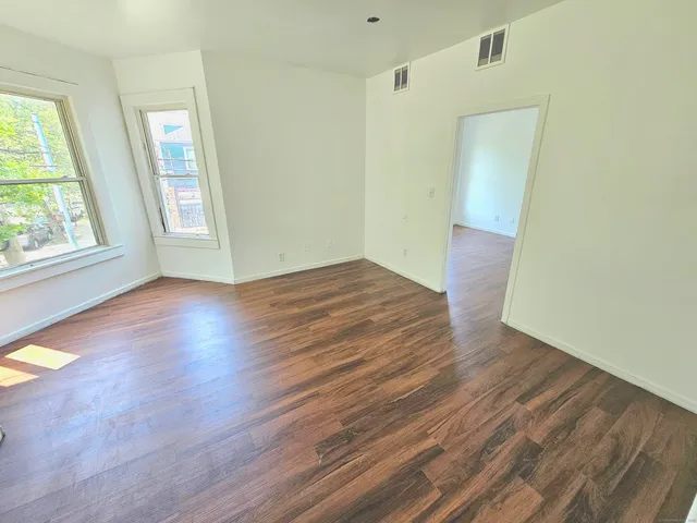an empty room with wooden floor and windows