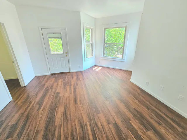an empty room with wooden floor and windows