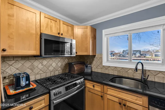a kitchen with granite countertop a stove a sink and a microwave