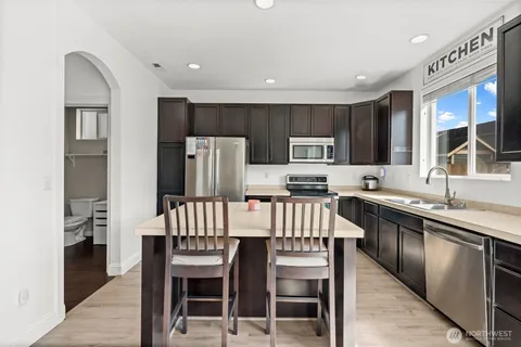 a kitchen with a refrigerator a stove a sink and chairs