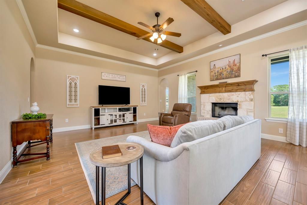 3224 North Cardinal Road Azle, TX 76020 - Photo 12 of 40 Spacious living area featuring ceramic tile flooring, a tray ceiling with exposed wood beams, and a ceiling fan