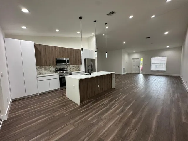 a large kitchen with stainless steel appliances kitchen island a large counter top and a stove top oven