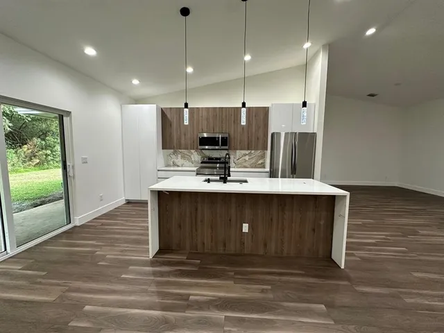 a kitchen with kitchen island a sink stainless steel appliances and cabinets
