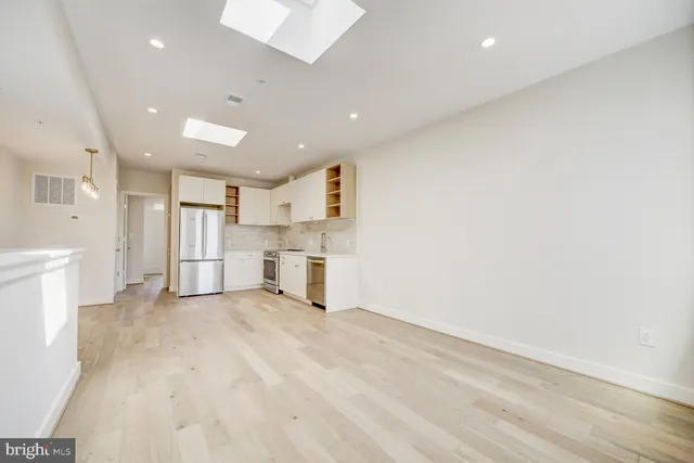 a view of a kitchen with white cabinets and wooden floor