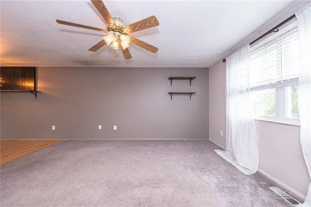 an empty room with windows and fan