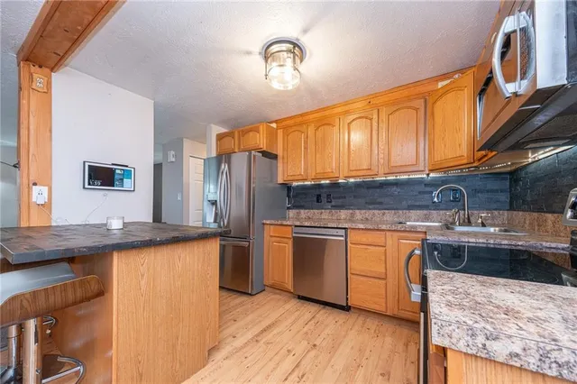 a kitchen with stainless steel appliances granite countertop a sink stove and refrigerator