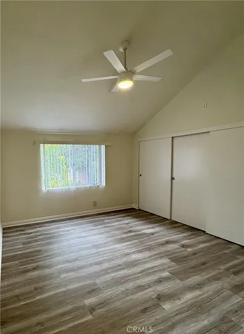 an empty room with wooden floor fan and windows