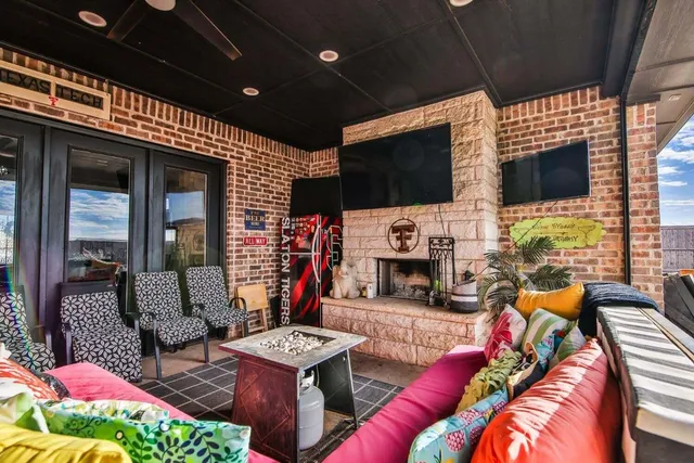 a outdoor living space with furniture a flat screen tv and a fireplace