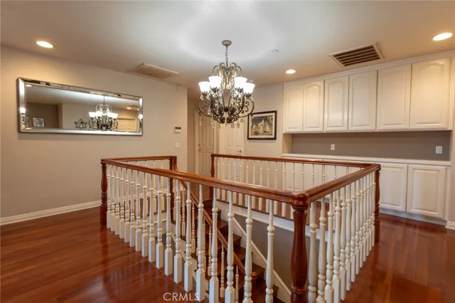 a dining room with wooden floor a chandelier a wooden table and chairs