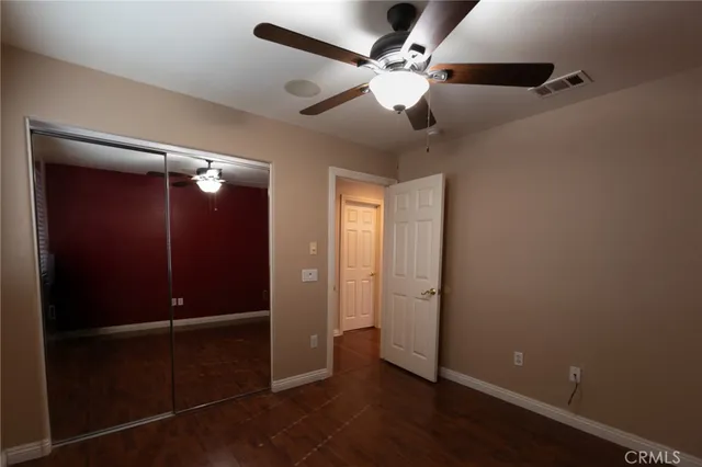 an empty room with closet and a chandelier fan