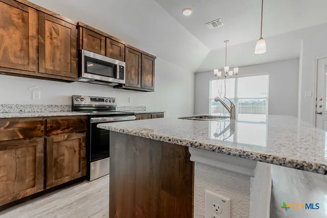 a kitchen with stainless steel appliances granite countertop a sink a stove and a microwave