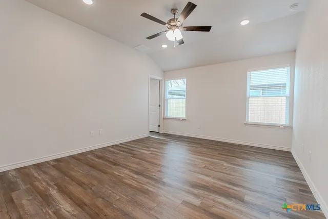 an empty room with wooden floor and windows
