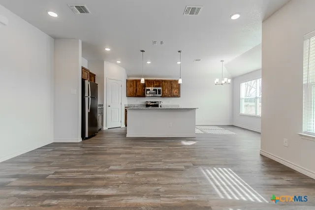 a view of kitchen with stainless steel appliances granite countertop a refrigerator and a stove top oven