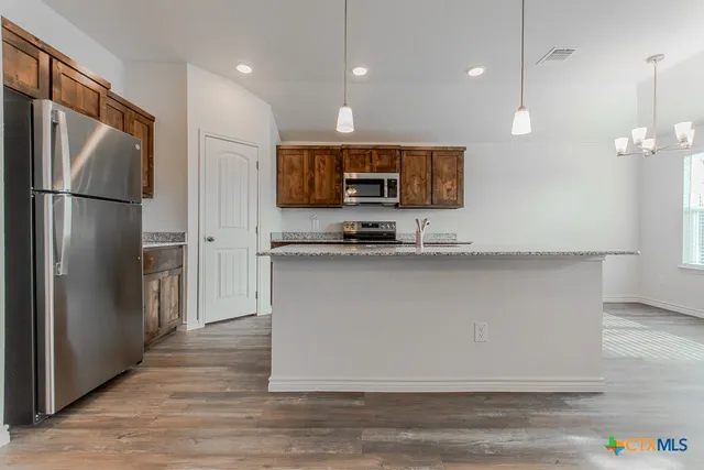 a kitchen with kitchen island a counter top space stainless steel appliances and cabinets