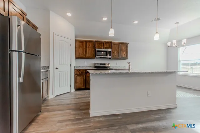 a kitchen with kitchen island a counter top space stainless steel appliances and a window