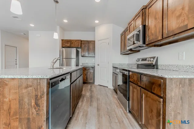 a kitchen with granite countertop a sink a counter space stainless steel appliances and cabinets