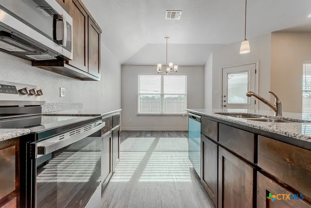 a kitchen with stainless steel appliances granite countertop a sink a stove and a wooden floors