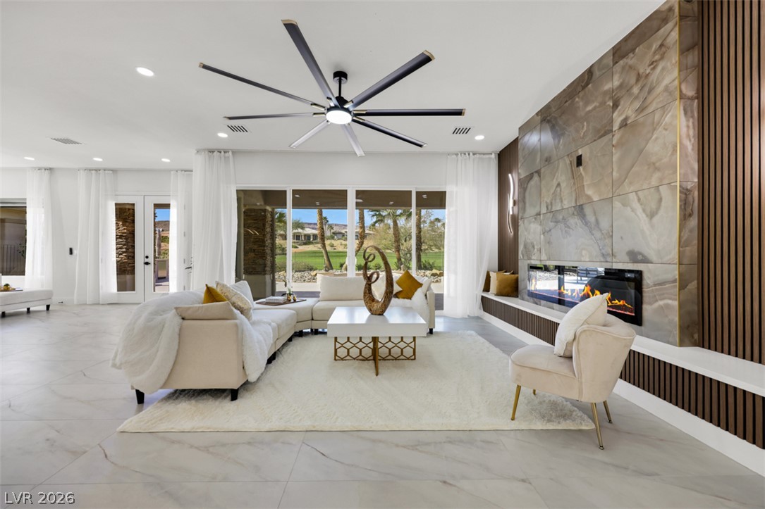 5015 Rivedro Street Las Vegas, NV 89135 - Photo 3 of 91 A spacious living area with a contemporary fireplace and broad glass doors opening to a scenic view.