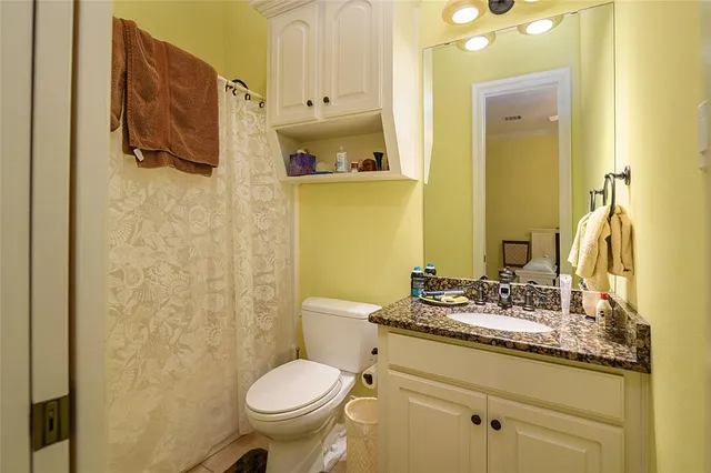 a bathroom with a granite countertop toilet sink and mirror