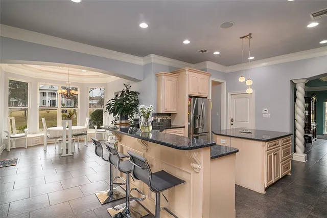 a dining hall with stainless steel appliances kitchen island granite countertop a living room view and furniture