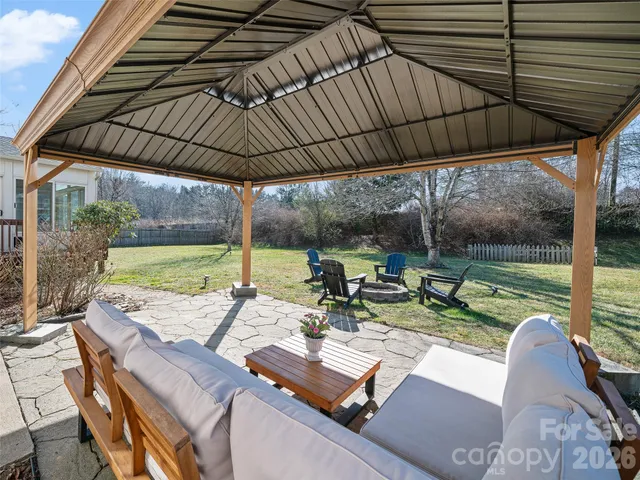 a view of a patio with table and chairs under an umbrella with a small yard
