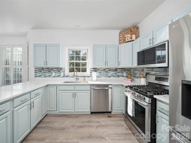 a kitchen with cabinets appliances a sink and a window