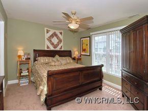 57 Round Top Road Asheville, NC 28803 - Photo 5 of 11 a spacious bedroom with a bed and a chandelier