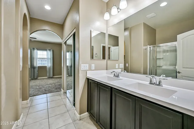a bathroom with a double vanity sink mirror and next to a window