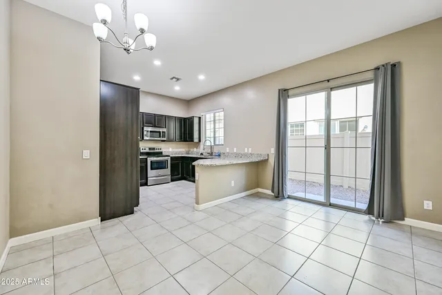 a large kitchen with kitchen island granite countertop a refrigerator a sink dishwasher a stove and white cabinets with wooden floor