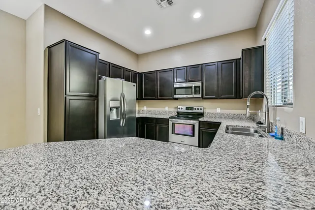 a kitchen with stainless steel appliances granite countertop a refrigerator sink stove microwave and cabinets