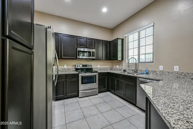 a kitchen with stainless steel appliances granite countertop a refrigerator stove and sink
