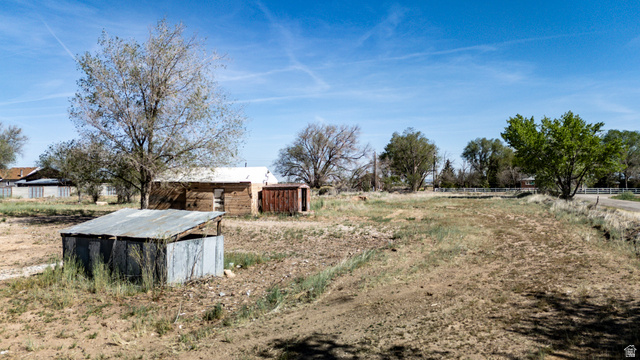 1211 West Midvalley Road Cedar City, UT 84721 - Photo 12 of 14 Expansive open land featuring a detached shed with a metal roof and a wood-sided structure with a white roof