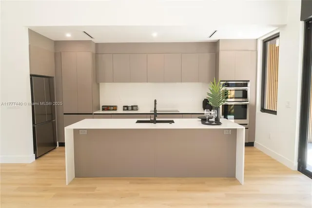 a large kitchen with wooden floor and stainless steel appliances