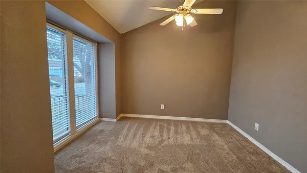 a view of an empty room with window and chandelier fan