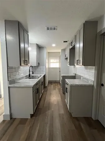 a large kitchen with a sink and dishwasher a stove top oven with wooden floor